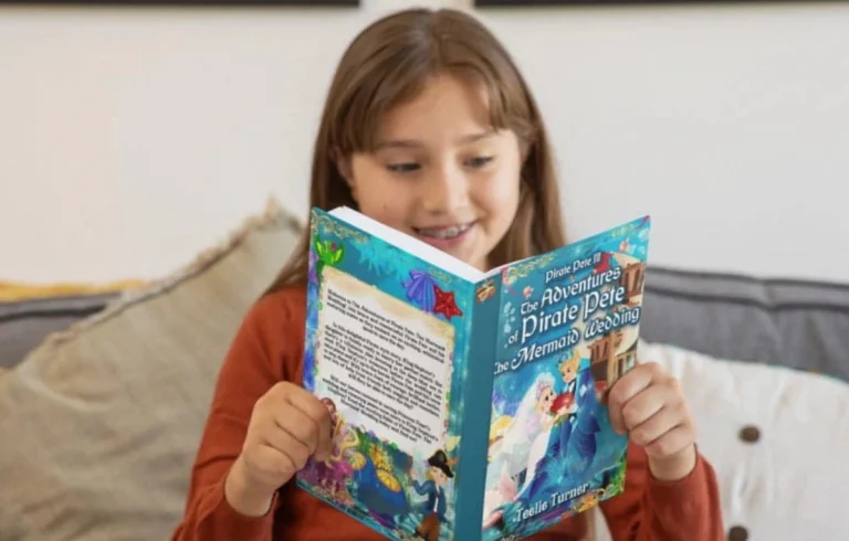 A young girl sitting on a couch, smiling while reading a colorful children's book titled The Adventures of Pirate Pete & The Mermaid Wedding, celebrating the joy of reading on World Book Day 2025.