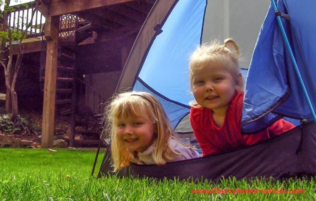 10 Summer Activities for Kids 8 Children enjoying a cozy backyard camping night with tents and string lights